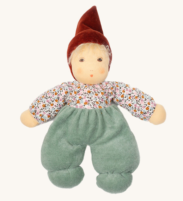 Nanchen Forest Child Waldorf Doll - Sage. This beautifully handcrafted doll wears sage velour trousers, a brown hat and a floral top. On a cream background