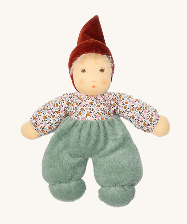 Nanchen Forest Child Waldorf Doll - Sage. This beautifully handcrafted doll wears sage velour trousers, a brown hat and a floral top. On a cream background