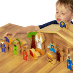 A child playing with the Wooden Lanka Kade Deluxe Nativity Set figures on a wooden table