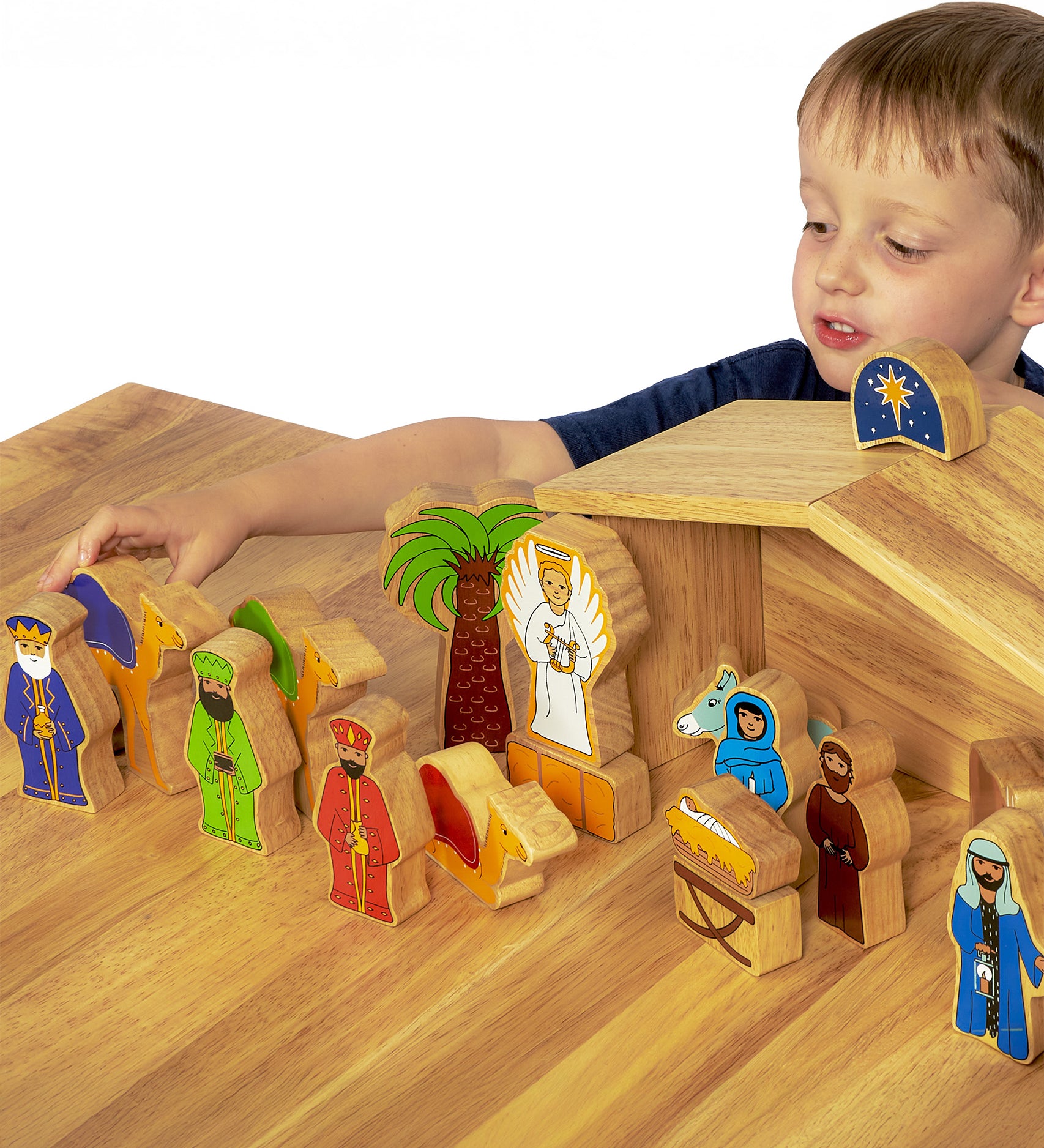 A child playing with the Wooden Lanka Kade Deluxe Nativity Set figures on a wooden table