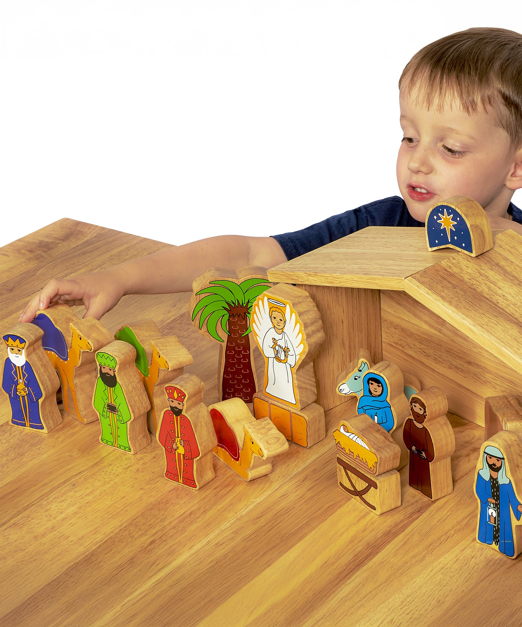 A child playing with the Wooden Lanka Kade Deluxe Nativity Set figures on a wooden table