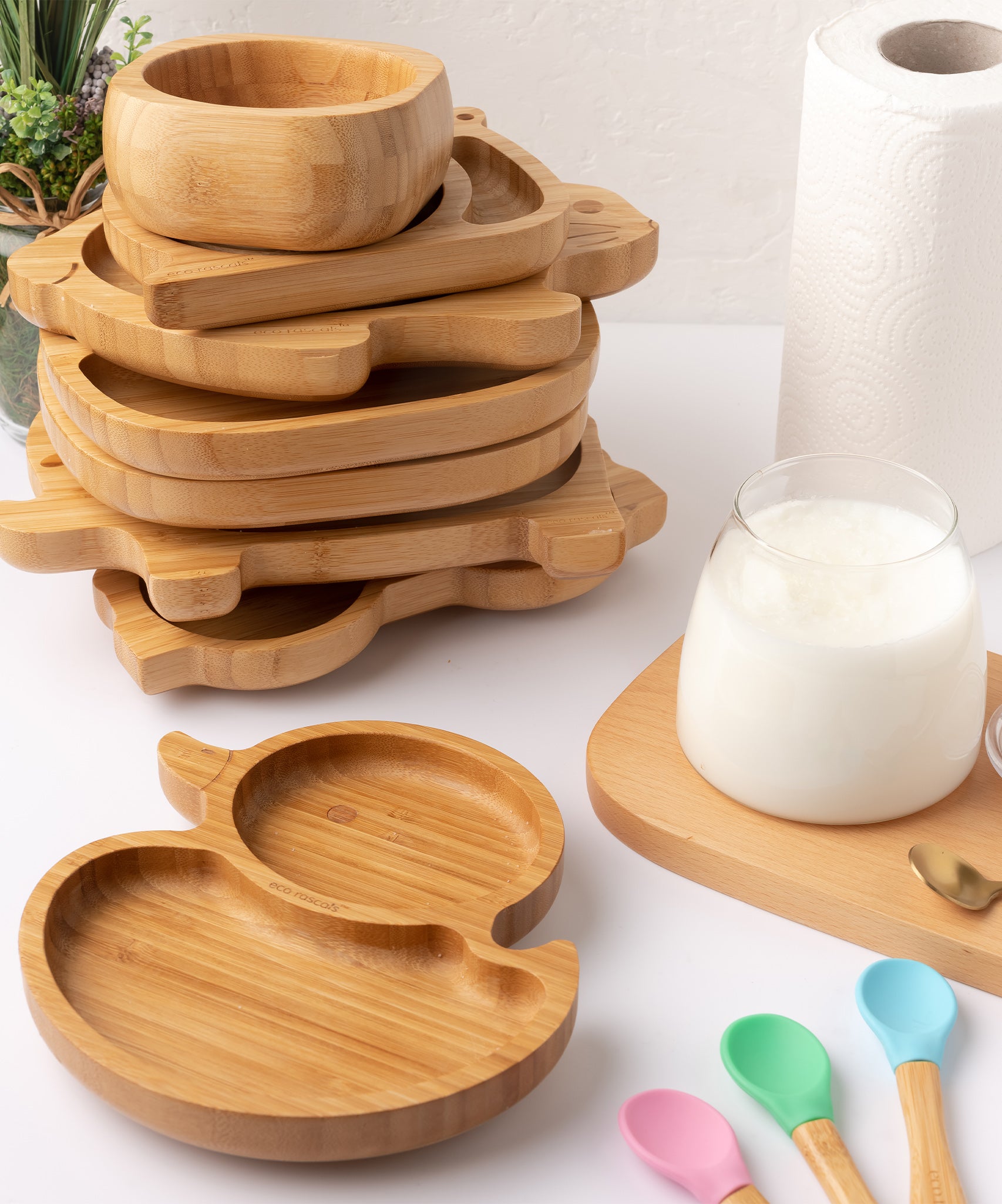 Eco Rascals Duck Bamboo Suction Plate, with a stack of other bamboo plates and bowl in the background. 