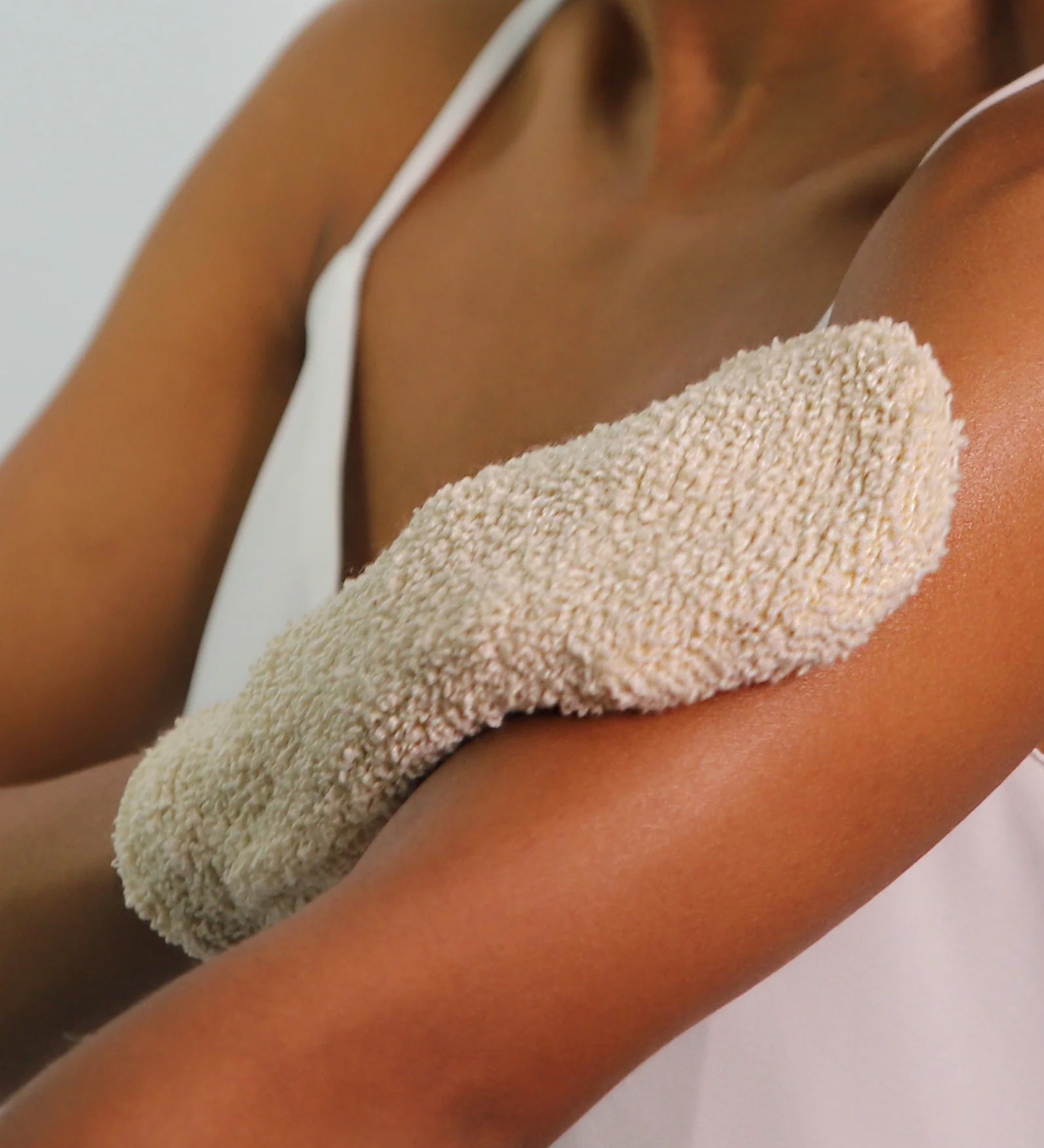 A person using the Green People Exfoliating Mitt on their arm