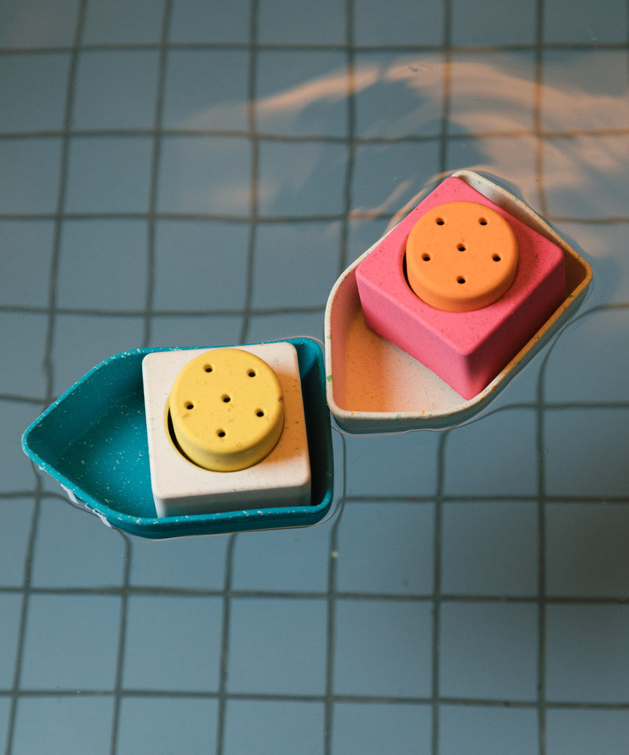 The Oli & Carol Boat Bath Toys floating together on water in a blue tiled bath