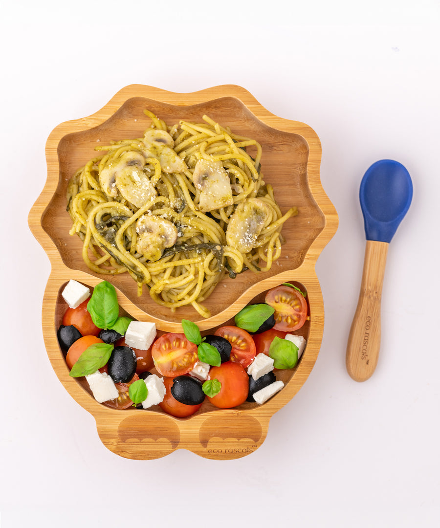 Eco Rascals Dinosaur Bamboo Suction Plate with spaghetti and mushrooms with a Greek salad side, and blue silicone and bamboo baby spoon.