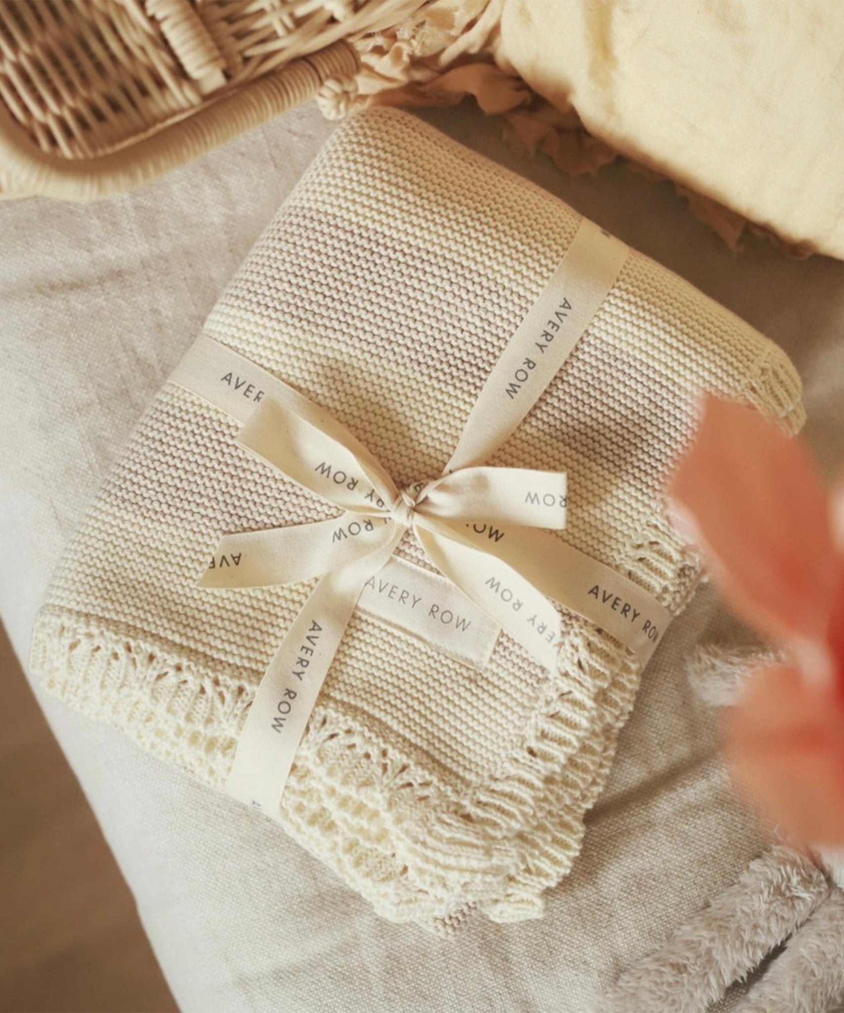 Avery Row Stripe Knit Organic Baby Blanket - Oat Melange, folded with branded ribbon on a changing table. 