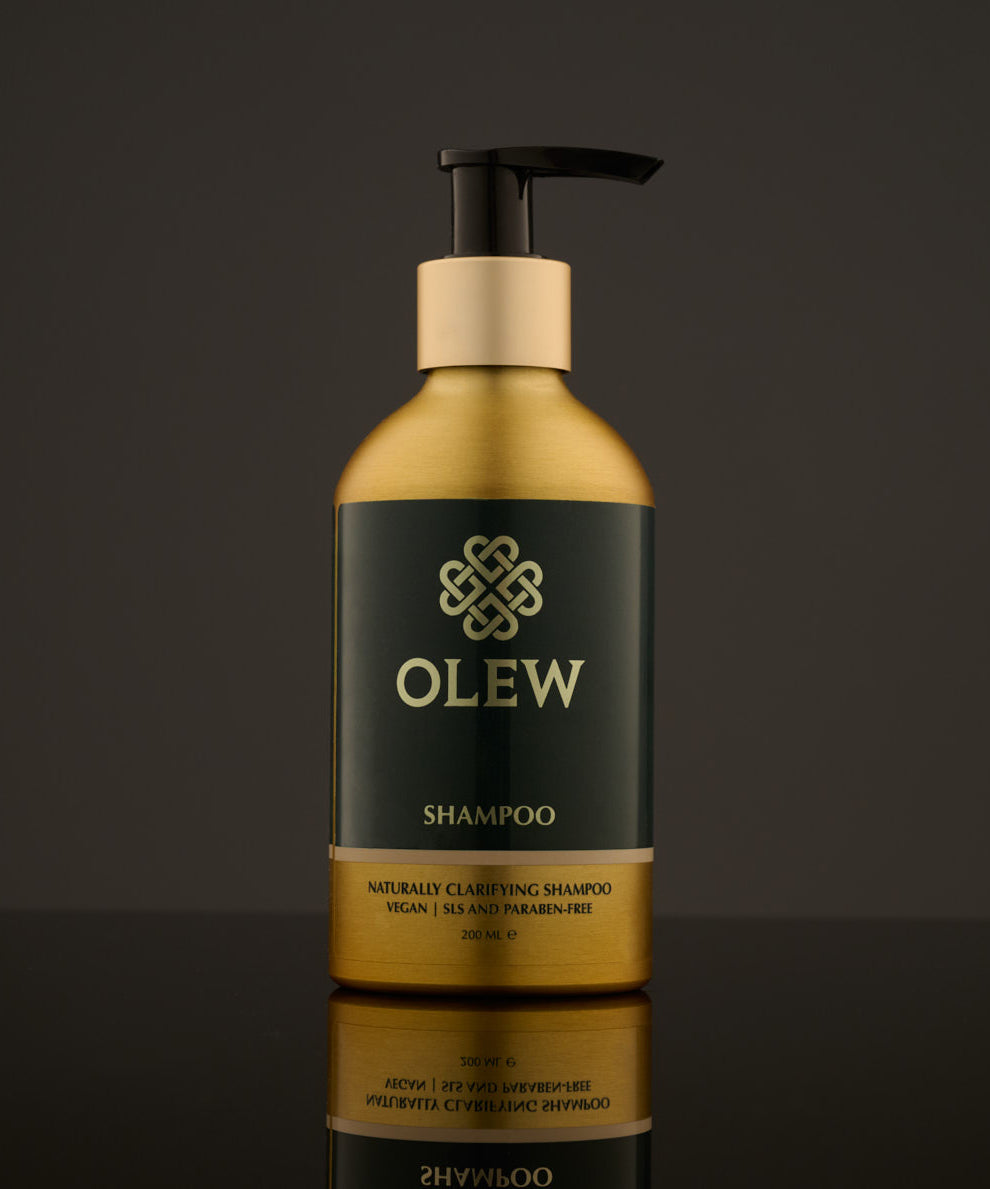 Olew Clarifying Shampoo, vegan haircare which is SLS and Paraben Free, in a gold and dark green bottle with a push down pump on top. The image is on a dark grey background