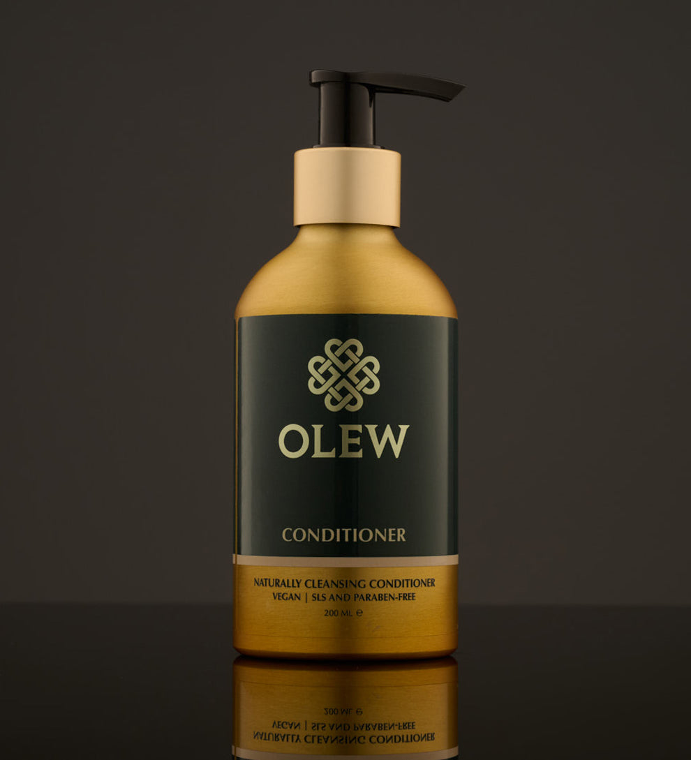 Olew naturally cleansing Conditioner, vegan haircare which is SLS and Paraben Free. In a gold and dark green bottle with a push down pump on top. The image is on a dark grey background