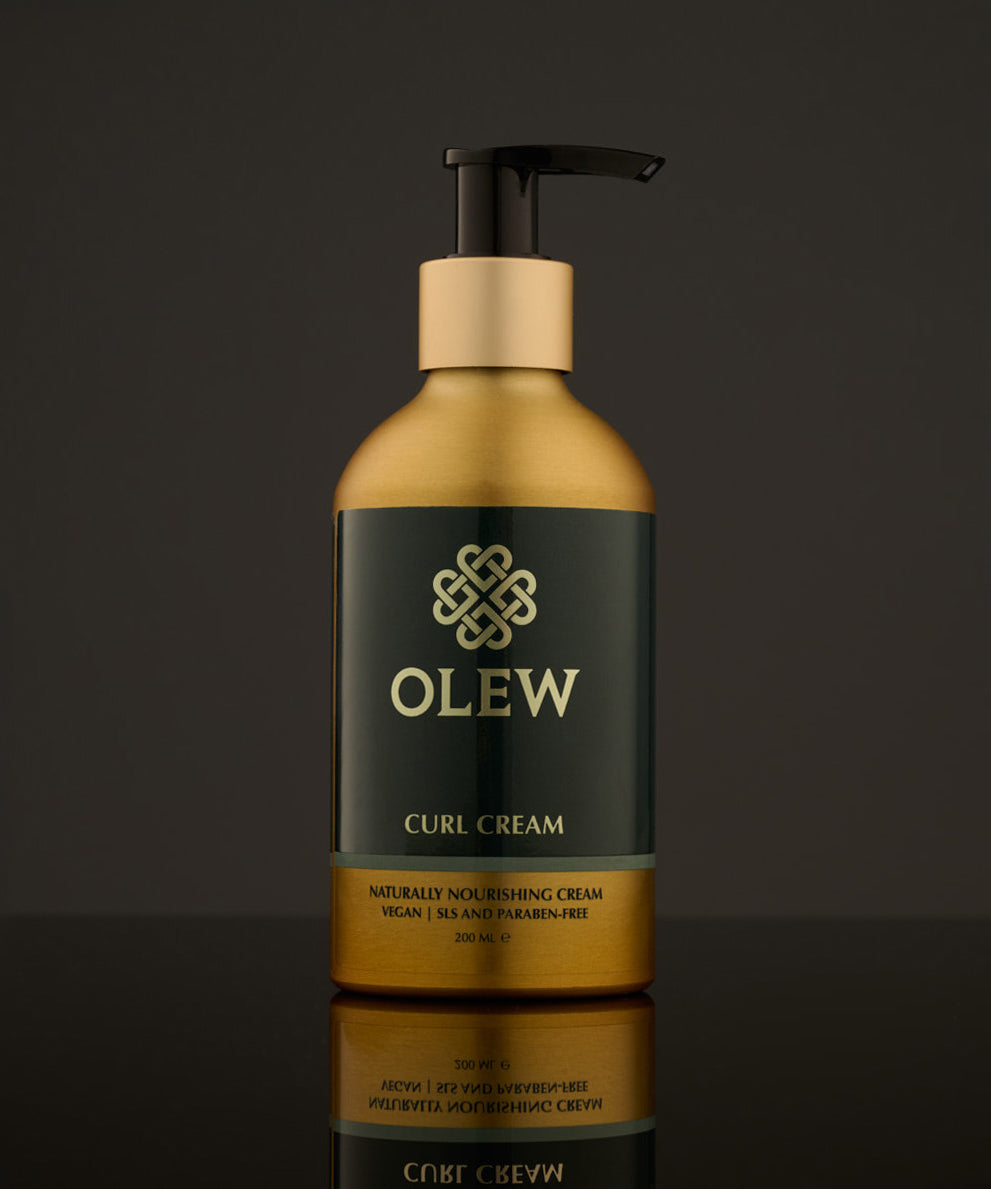 Olew Naturally Nourishing Curl Defining Cream, vegan haircare which is SLS and Paraben Free in a gold and dark green bottle with an push down pump top, on a dark grey background