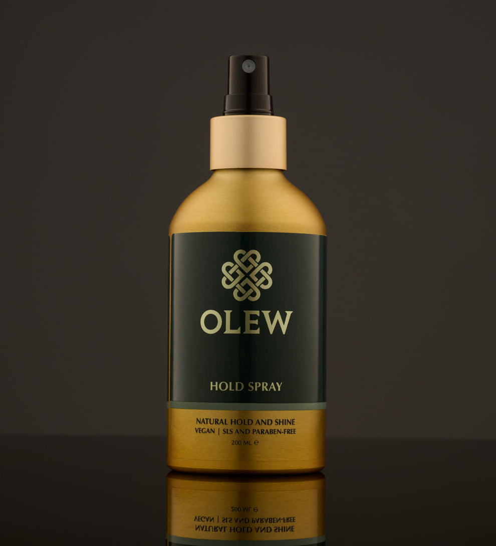 Olew Hold Spray - Curl Keeper, giving natural hold and shine. Vegan haircare which is SLS and Paraben Free, in a gold and dark green bottle with a spray mist pump on top. The image is on a dark grey background