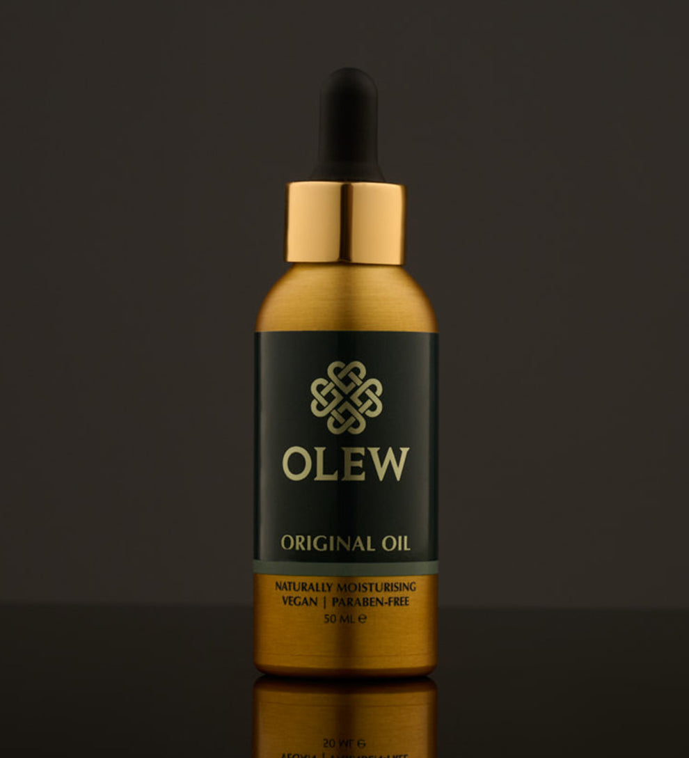 Olew Original Hair Oil, naturally moisturising vegan haircare which is SLS and Paraben Free, in a gold and dark green bottle with a pipette on top. The image is on a dark grey background