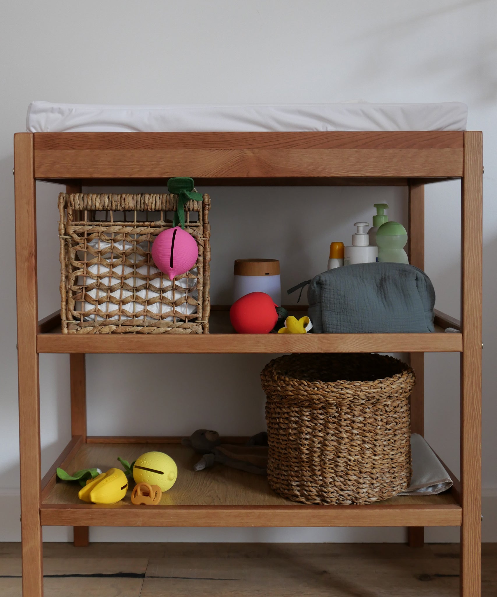 The Oli & Carol natural rubber pacifier holders are on a changing table with other baby changing items