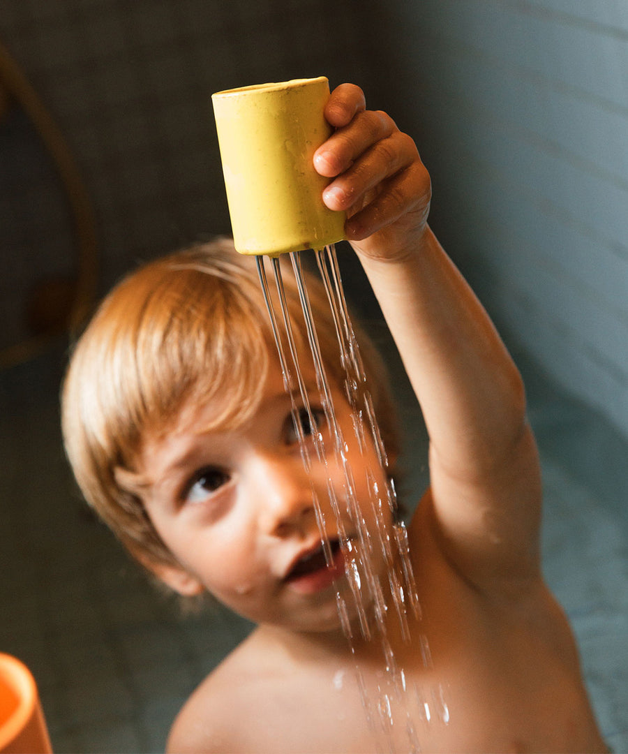 A child pouring water through a yellow piece of the natural rubber boat. This piece works like a shower head with holes in the bottom