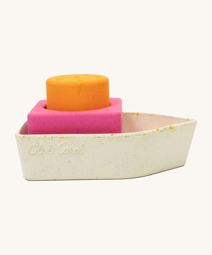 A closer look at the Oli & Carol Boat Bath Toy - Orange, from the side on a cream background. The boat has lots of small coloured pieces due to the material of the boat being upcycled