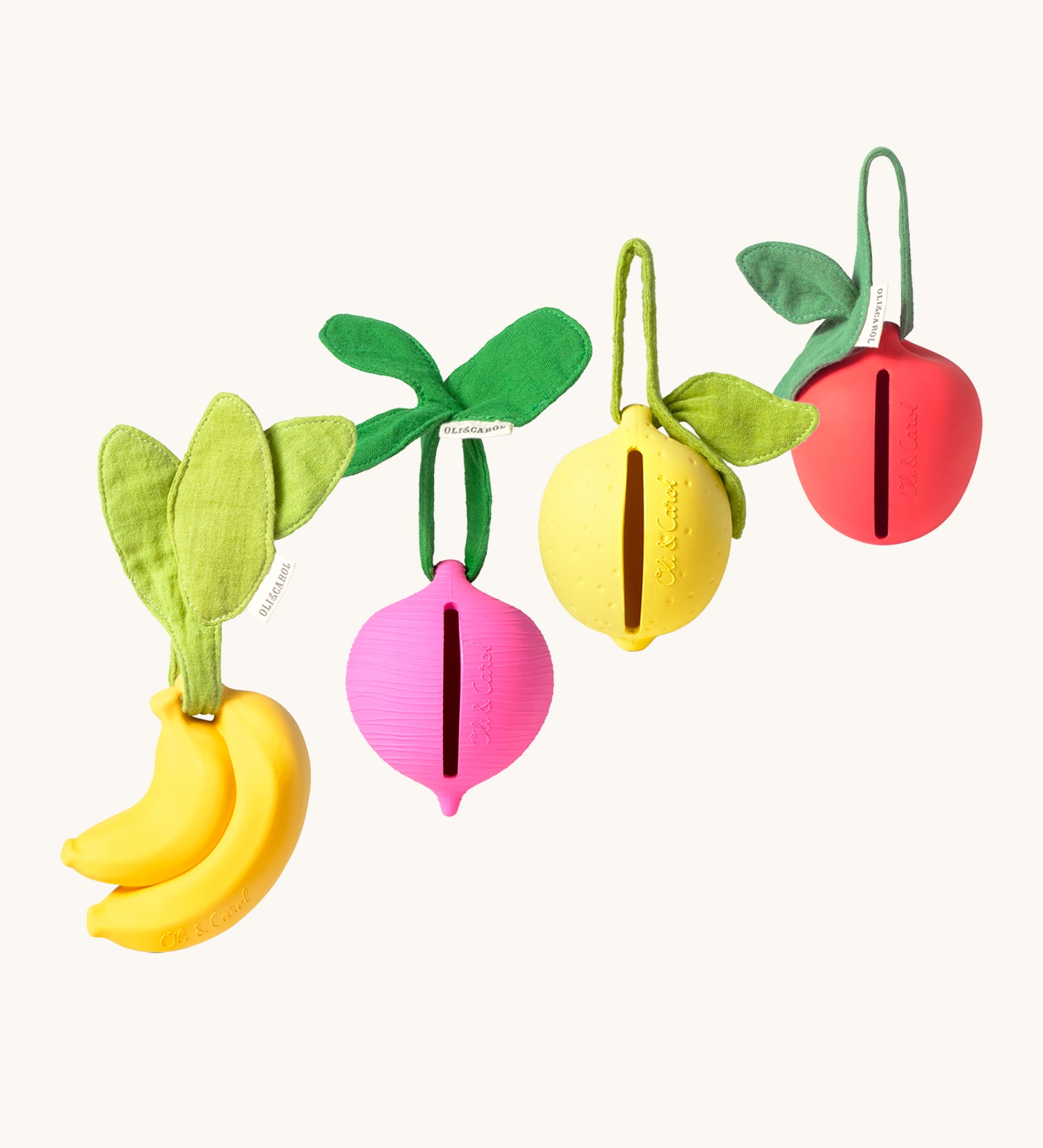 The Oil & Carol Fruit & Veggie Pacifier Cases, made from Natural Rubber in a diagonal row on a cream background. There is a yellow banana, a pink/purple radish, a yellow lemon and a red apple. The image also showing the slot where the pacifier/dummy fits into the holder case