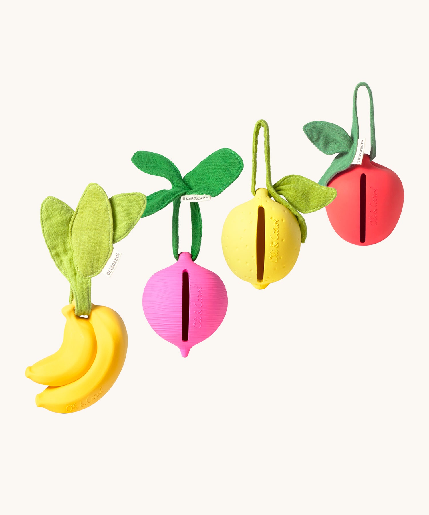 The Oil & Carol Fruit & Veggie Pacifier Cases, made from Natural Rubber in a diagonal row on a cream background. There is a yellow banana, a pink/purple radish, a yellow lemon and a red apple. The image also showing the slot where the pacifier/dummy fits into the holder case