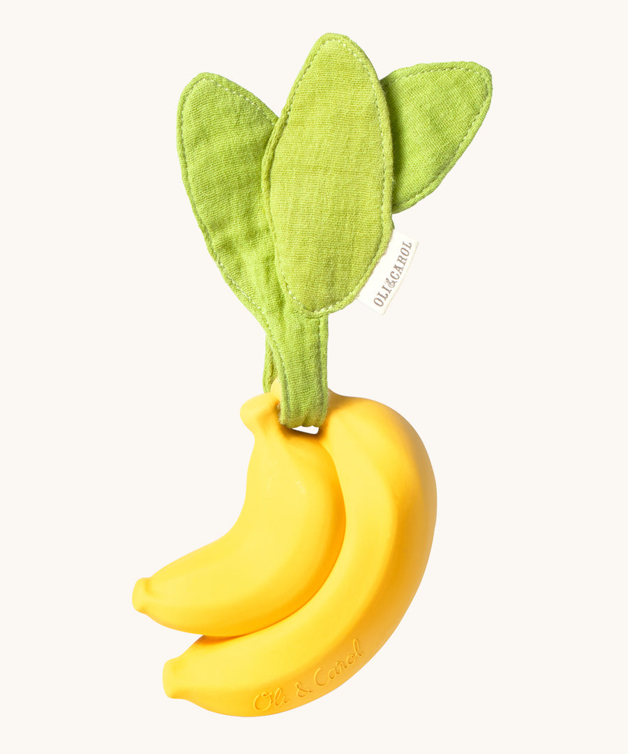 The Ana Banana Pacifier Holder on a cream background. The banana is smooth and has a green muslin leaf attachment on the top to tie the holder to a pram handle, high chair etc.