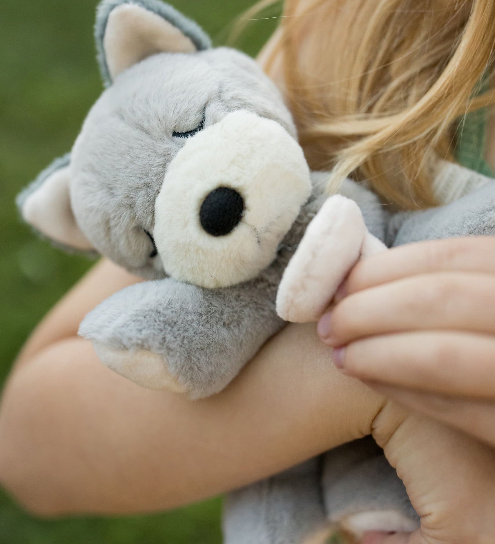 A child holding the soft grey Olli Ella dinkum puppy.