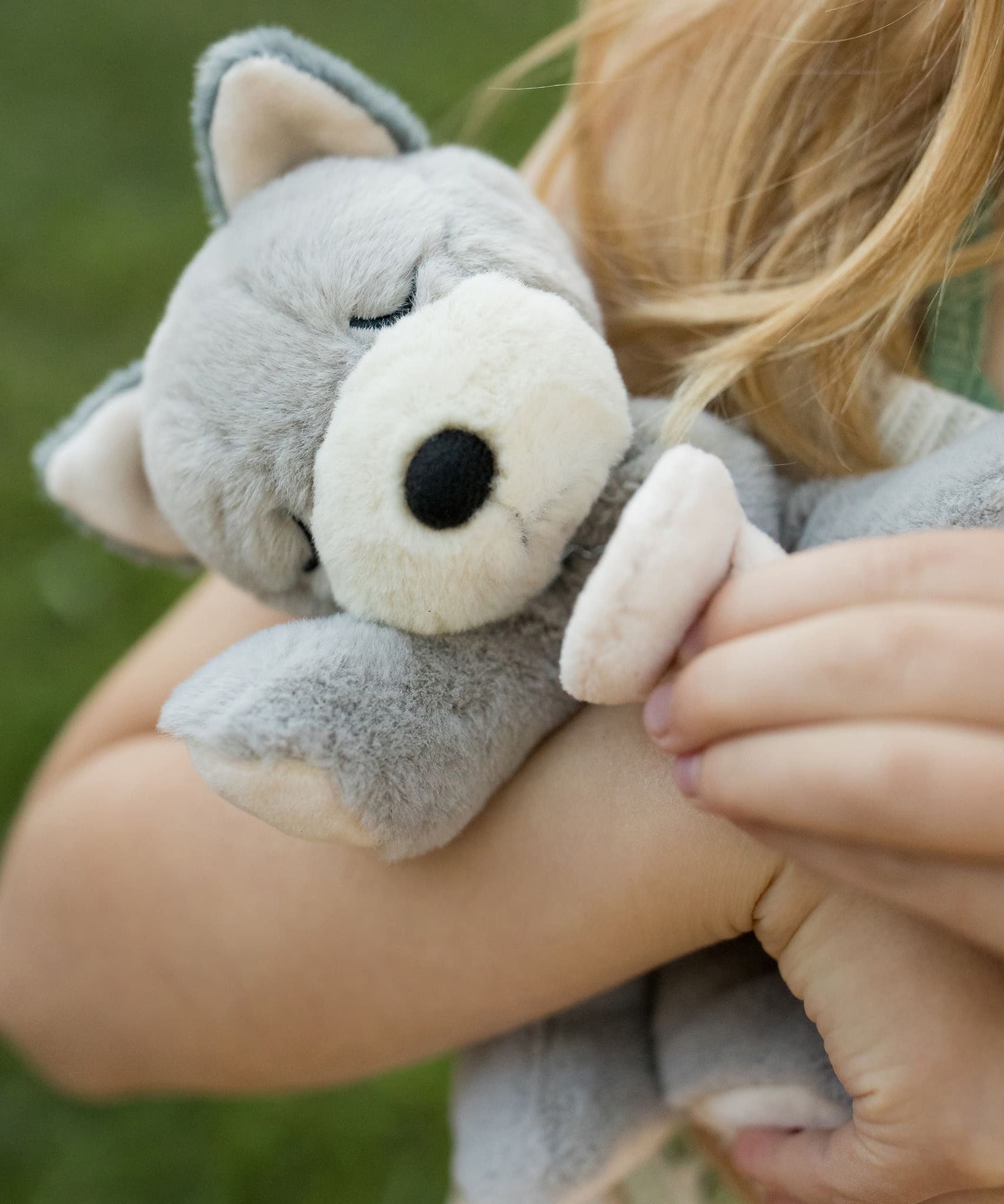 A child holding the soft grey Olli Ella dinkum puppy.