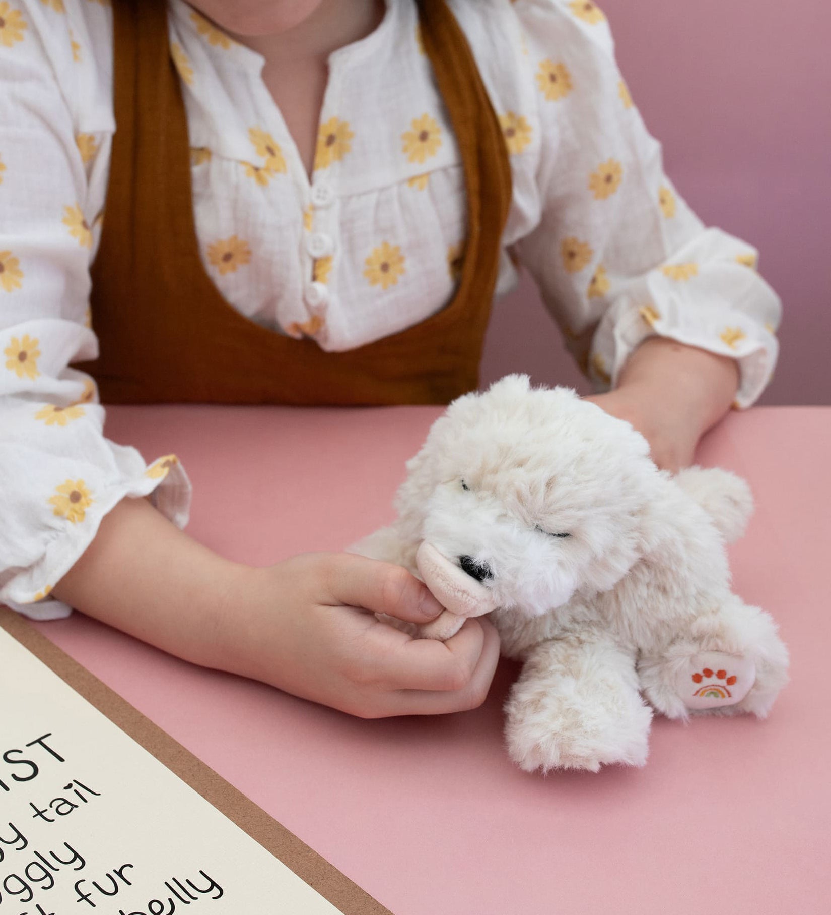 A child playing with the soft white Olli Ella Belle dinkum puppy.