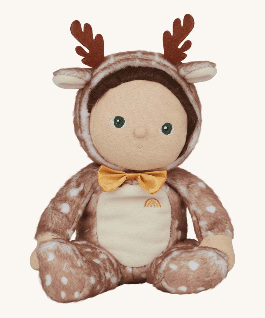 Olli Ella Dinky Dinkum Doll - Riley Reindeer is part of the festive, limited edition Jolly Dolly range from Olli Ella. Riley wears a soft, tan and white velvet onsie with a movable hood that has reindeer antlers and ears on top, dark hair, light skin and an adorable yellow bow tie on its neck. The image is on a cream background