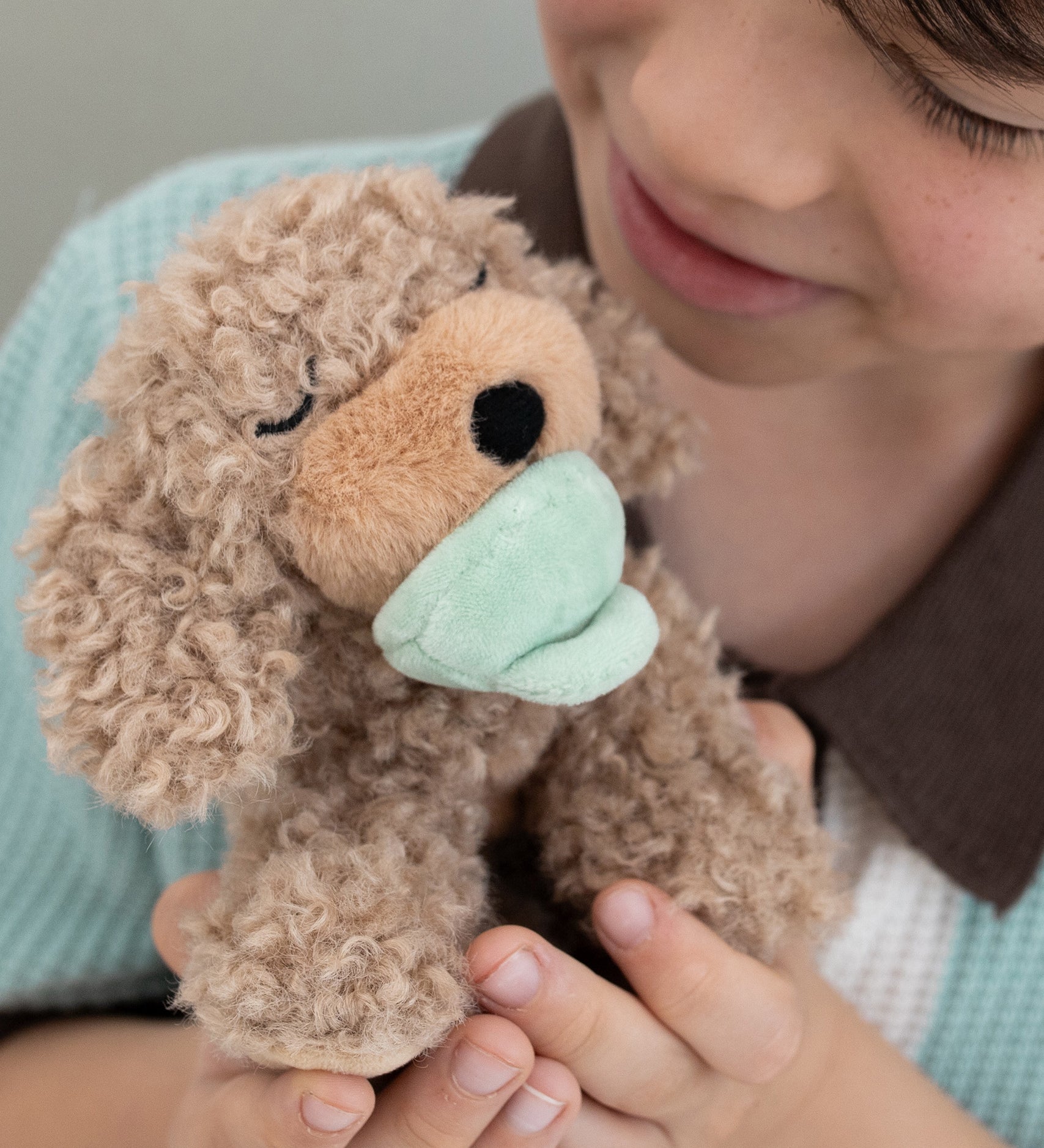 A child holding the soft and fluffy brown Benny Olli Ella dinkum doll