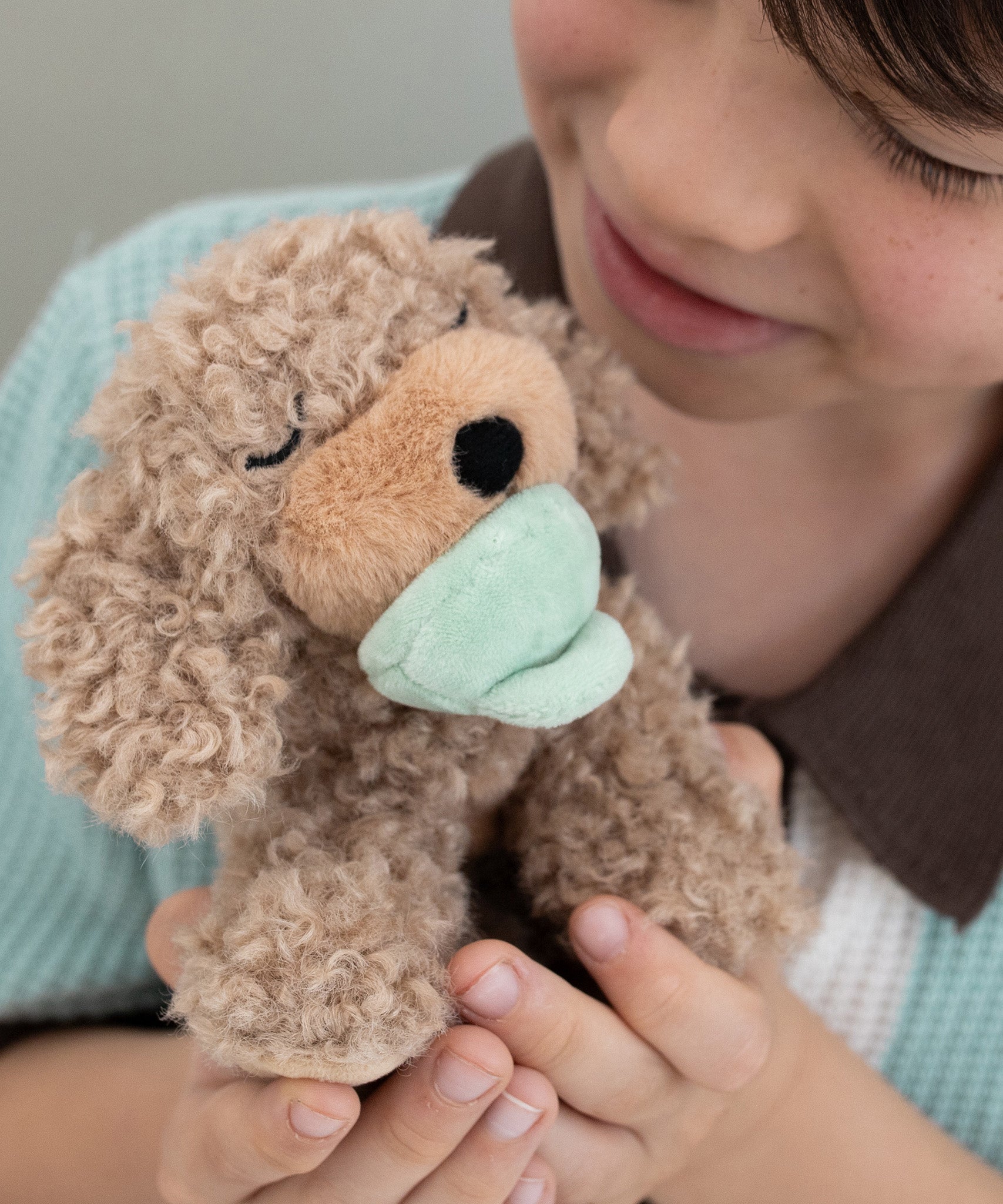 A child holding the soft and fluffy brown Benny Olli Ella dinkum doll