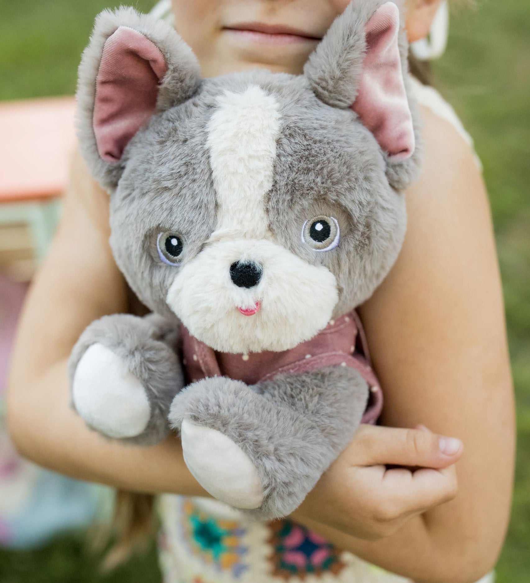 A child hugging the Olli Ella Gizmo dinkum dog. 