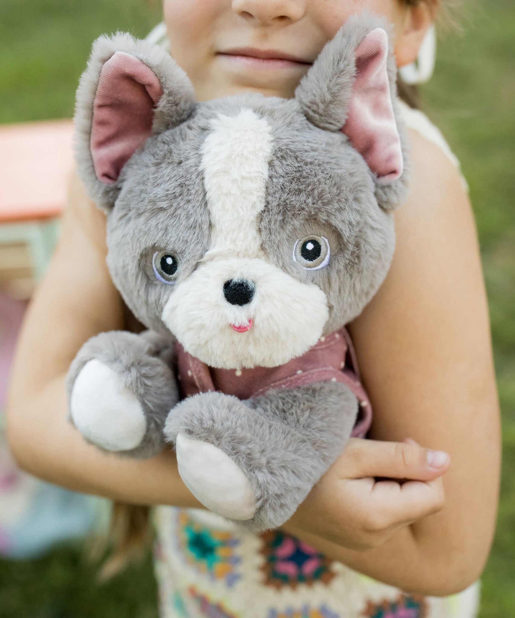 A child hugging the Olli Ella Gizmo dinkum dog. 