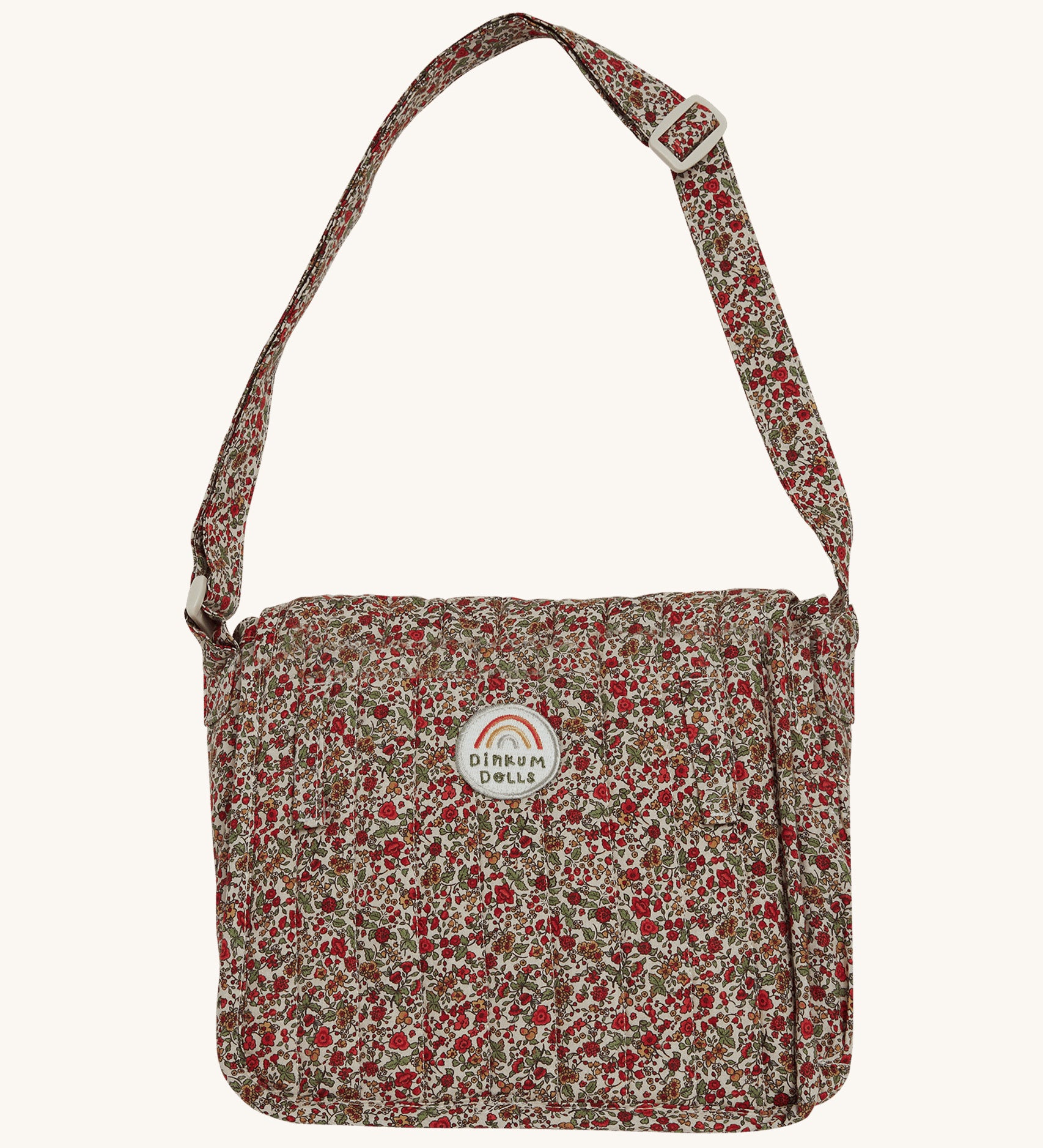 Olli Ella Carrie Convertible Changing Set - Garland. A beautiful floral print, cotton, changing bag for dolls and toys, with an adjustable shoulder strap. The changing bag coverts into a changing mat with the same floral print. The image is on a cream background