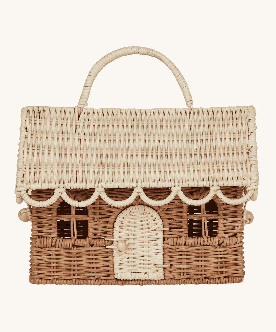 The Olli Ella Rattan Gingerbread House Basket - Natural & Straw, is a handwoven basket made to look like a festive gingerbread house. The lid is removable and the door on the font can open and close. The lid and door are a light cream colour and the main body of the basket is a darker brown colour. The image is on a cream background