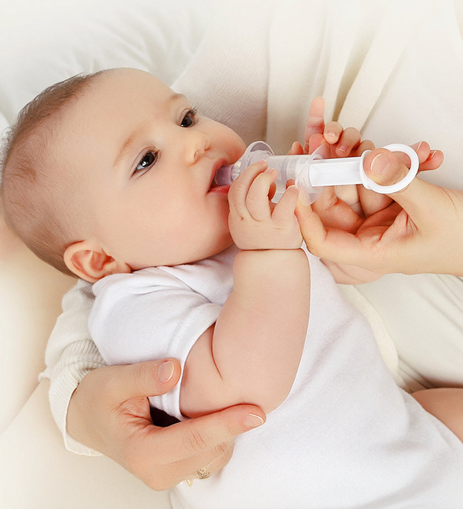 A parent using the Haakaa Oral Feeding Syringe with their child. The syringe tip is in the babies mouth a the parent is pushing the syringe plunger with their thumb