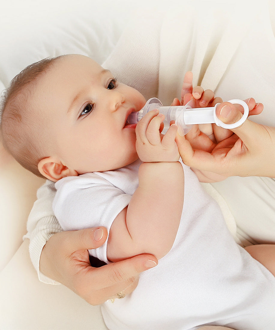 A parent using the Haakaa Oral Feeding Syringe with their child. The syringe tip is in the babies mouth a the parent is pushing the syringe plunger with their thumb