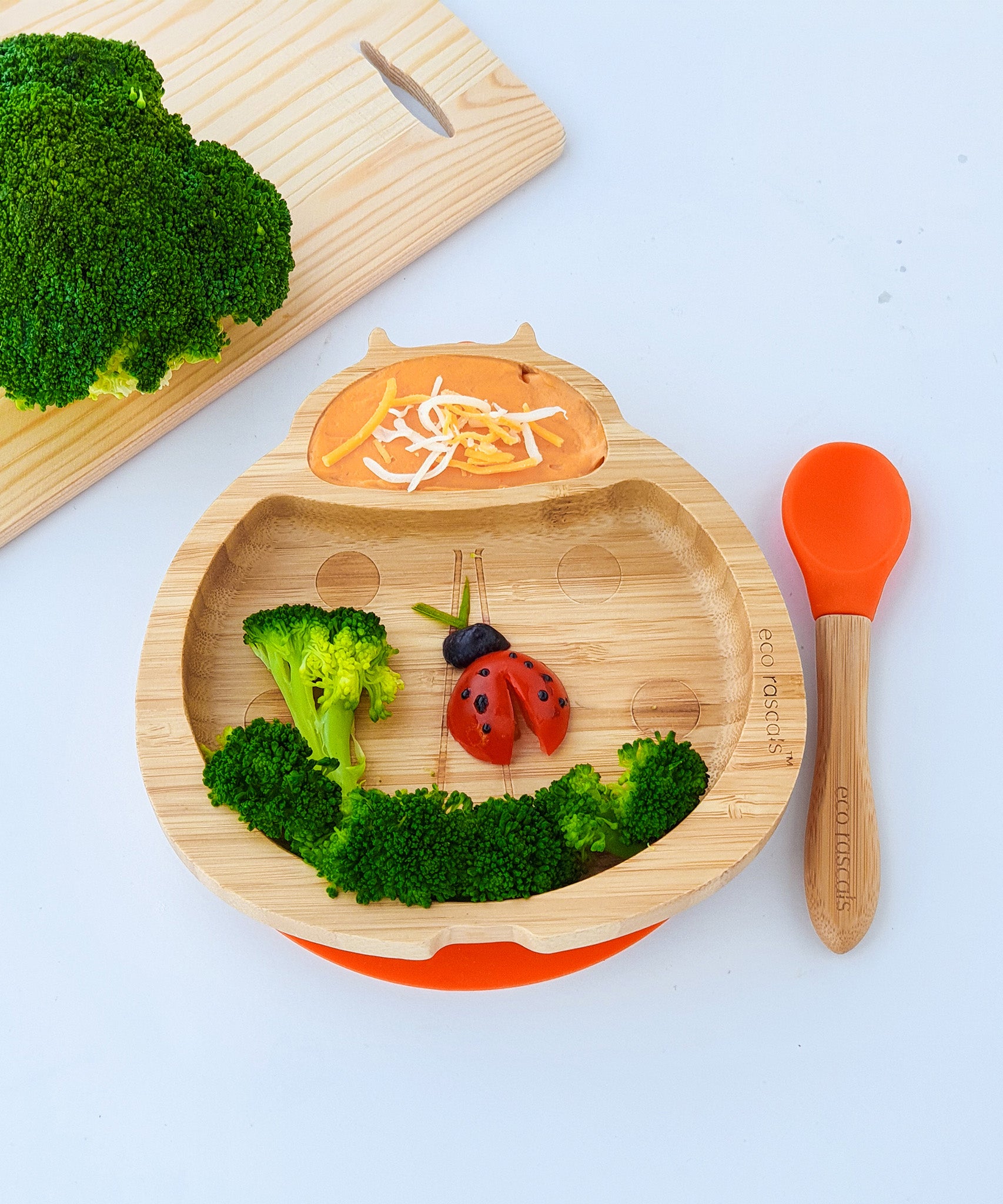 Eco Rascals Ladybird Bamboo Suction Plate with an orange silicone base and baby spoon, with broccoli and carrot puree. 