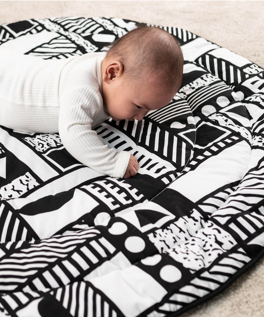 A child laying down, looking intensly at the monochromatic shape print, and enjoying the different shapes