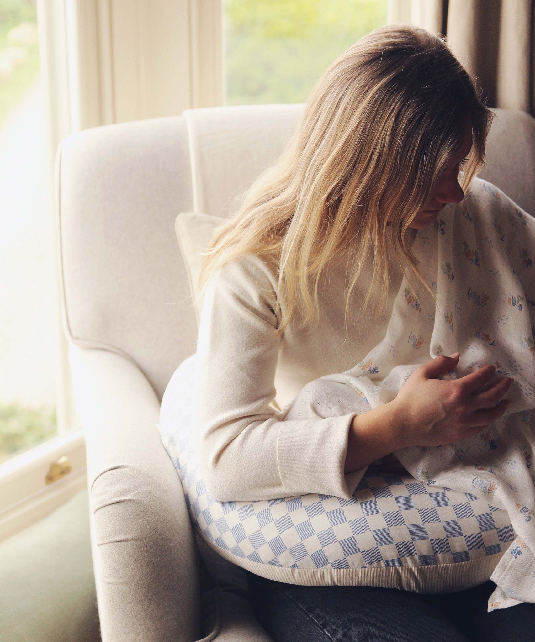 A mother feeding her baby on an Avery Row Nursing Pillow - Waves.