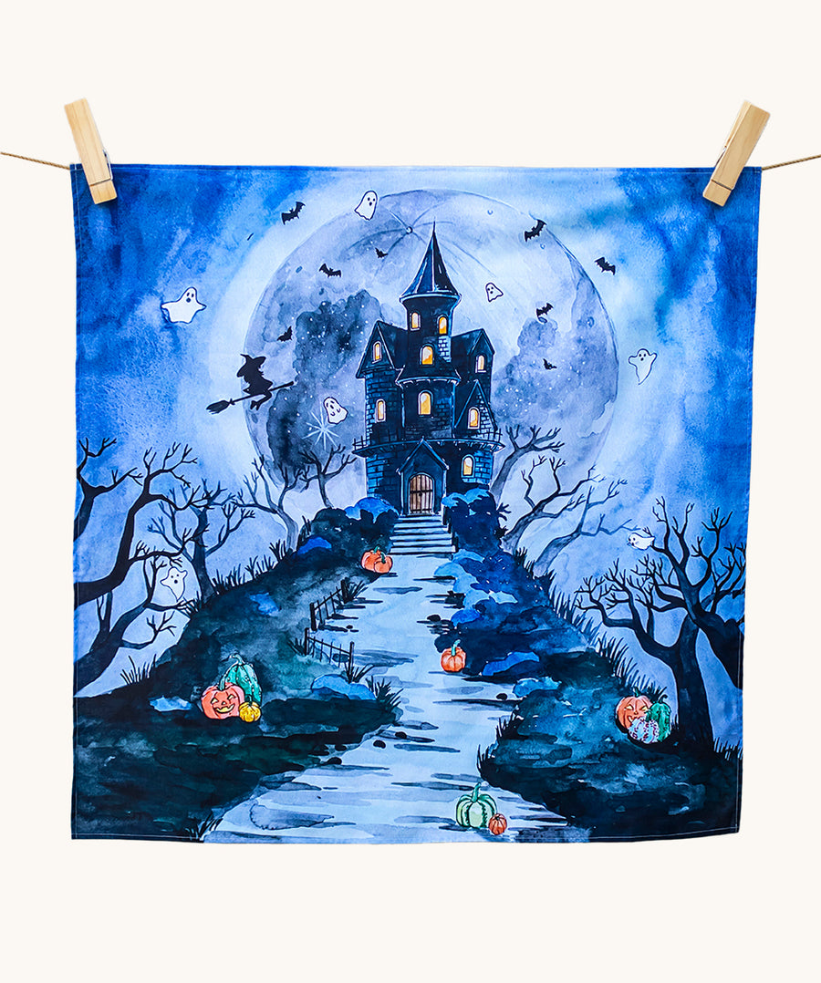 An organic play cloth with a fabulous spooky and Halloween print. A haunted manor on top of a steep hill side with stairs leading up to the door, has cute ghosts, bats and a witch circling around it. Behind the manor, is a large, full moon, and pumpkins outline the stairs and path to the manor