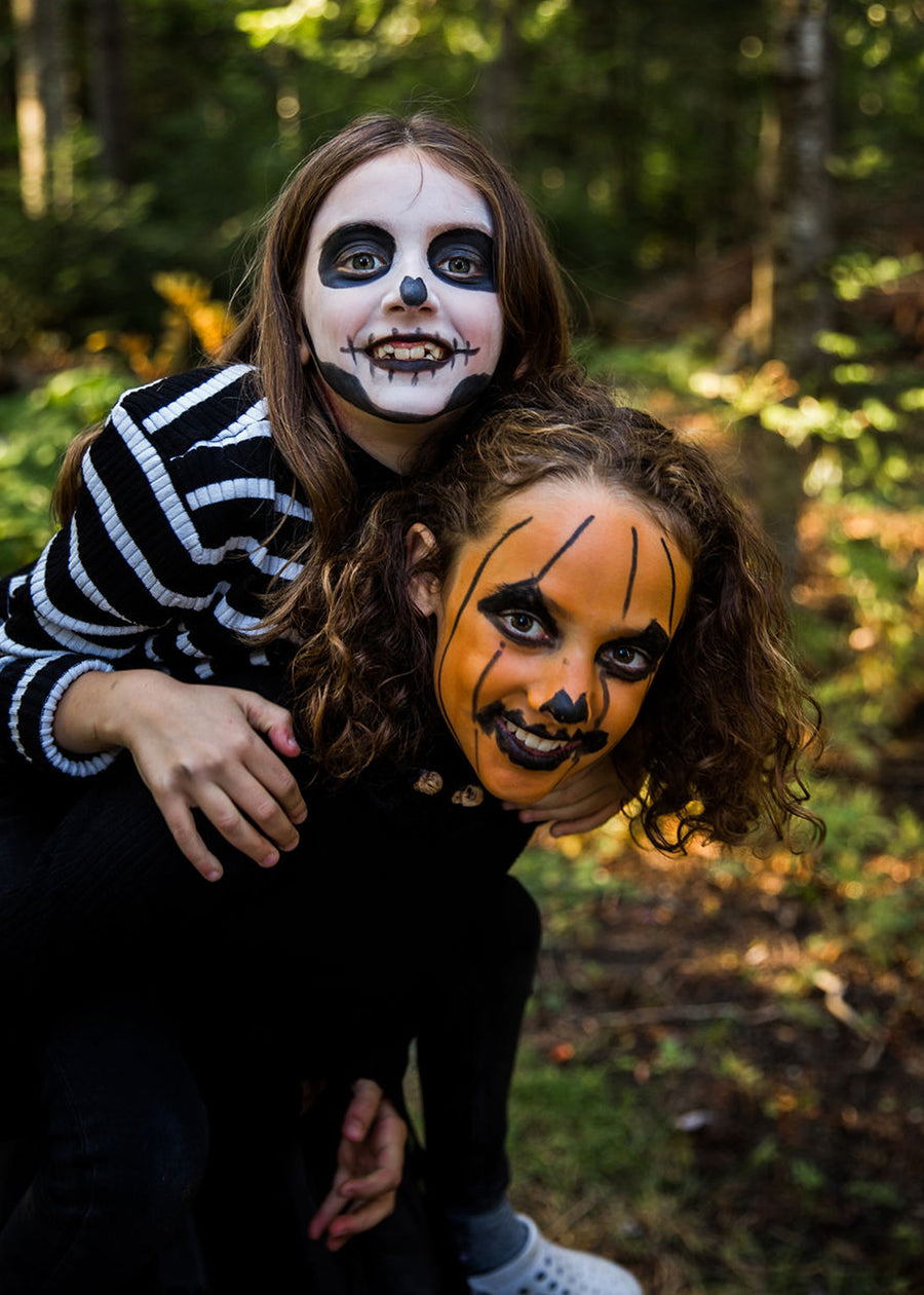 Two Children Playing in forest , they have Organic Halloween face paints an big smiles! 