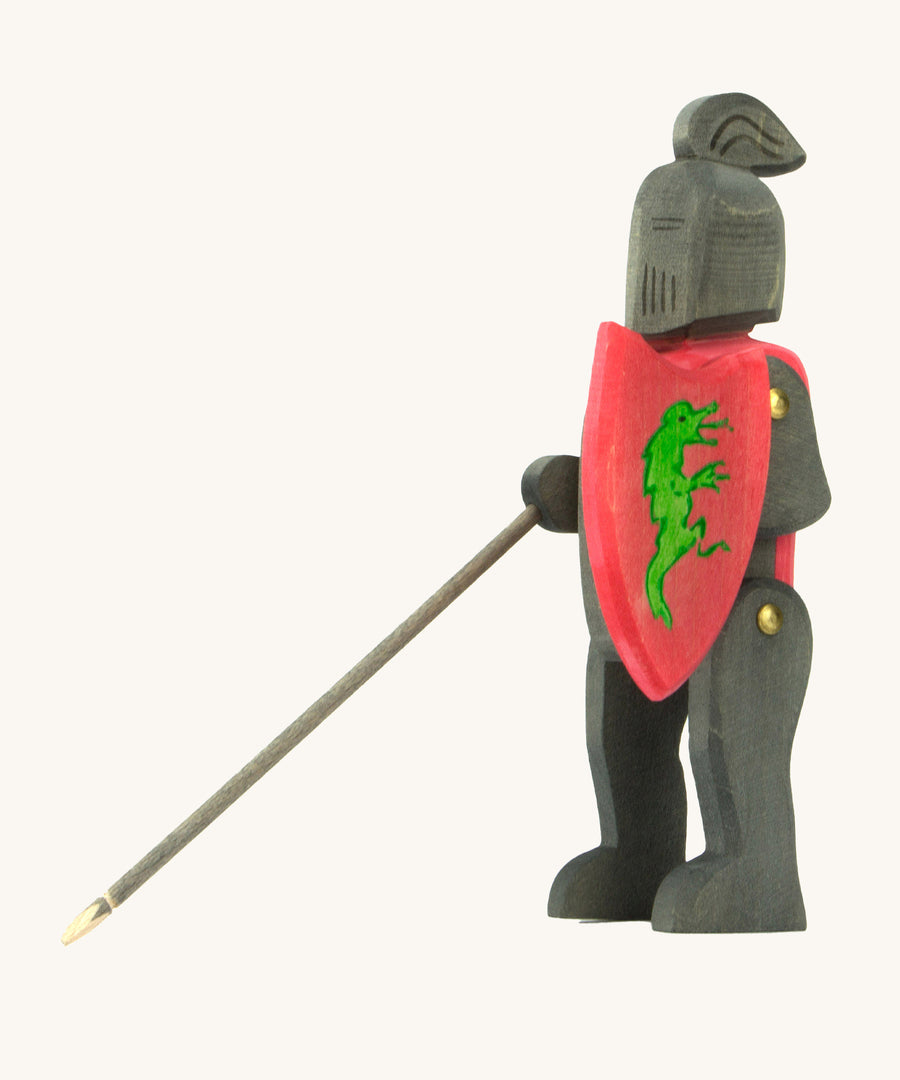 Ostheimer handmade and hand painted, wooden black knight. The knight holds a red shield with a green painted dragon on the front. This figure is also poseable with moving arms and legs.