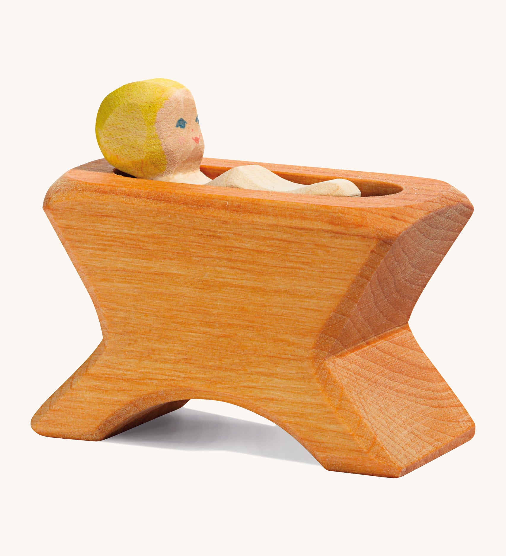 A Ostheimer wooden brown crib with a child lying inside the crib on a cream background.