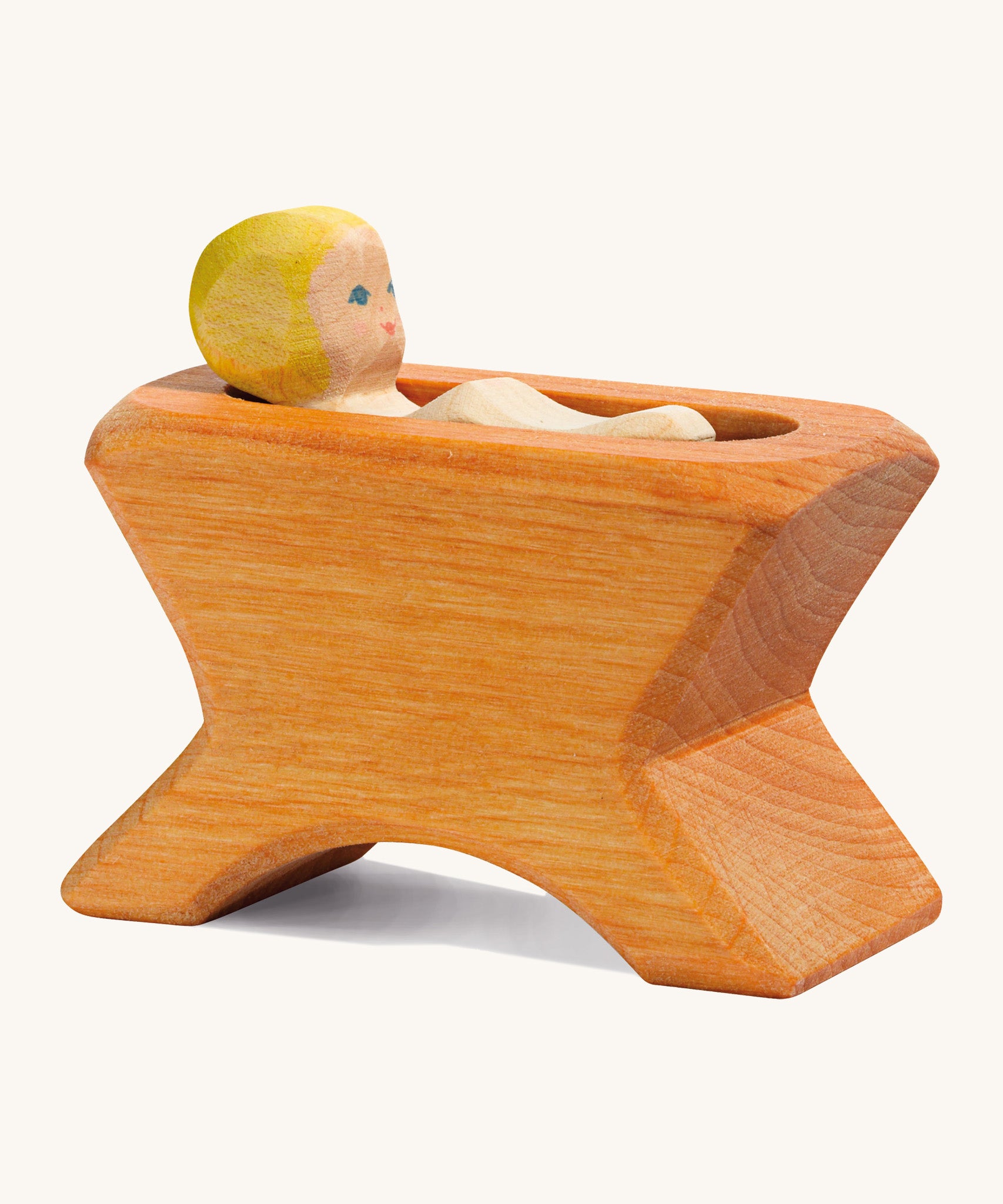 A Ostheimer wooden brown crib with a child lying inside the crib on a cream background.