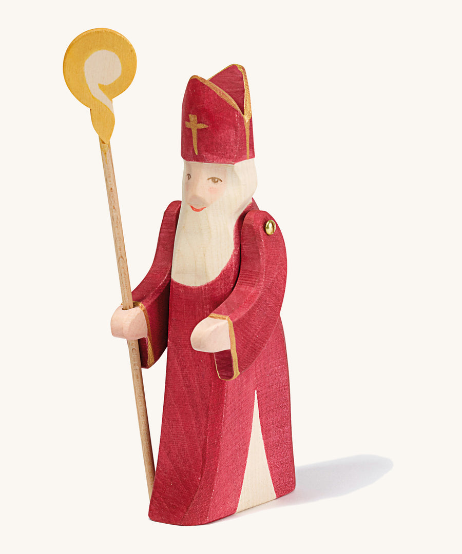 A Ostheimer wooden St Nicholas figure with moving arms holding a wooden staff on a cream background