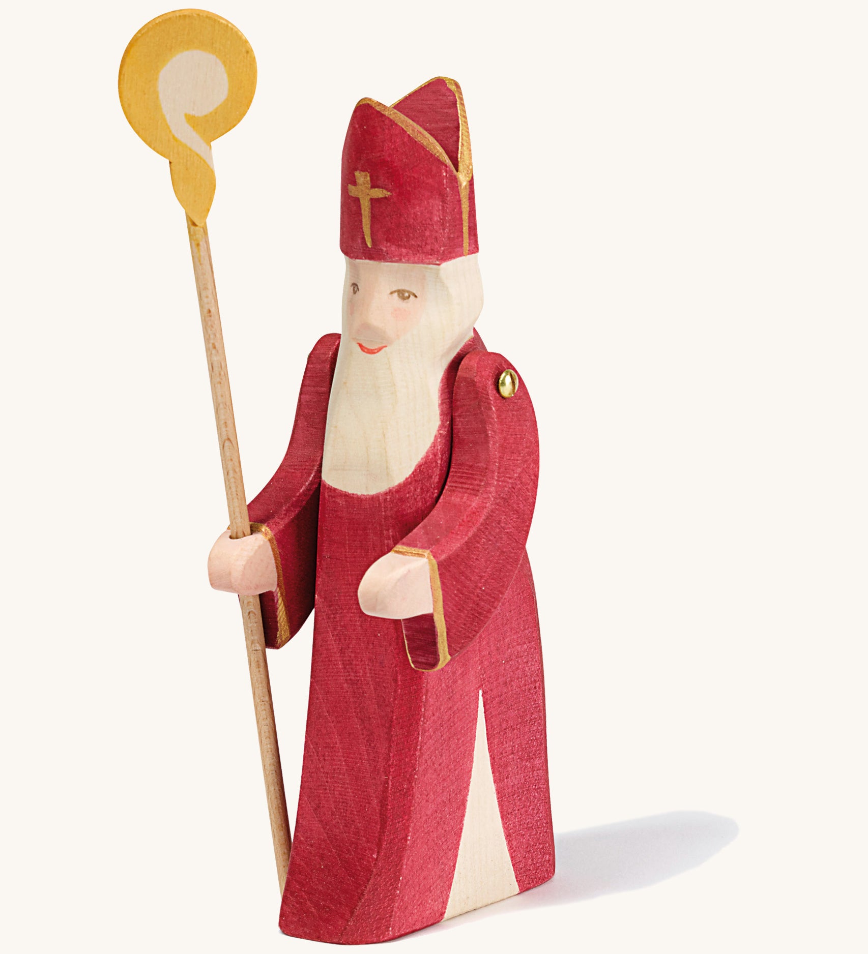 A Ostheimer wooden St Nicholas figure with moving arms holding a wooden staff on a cream background