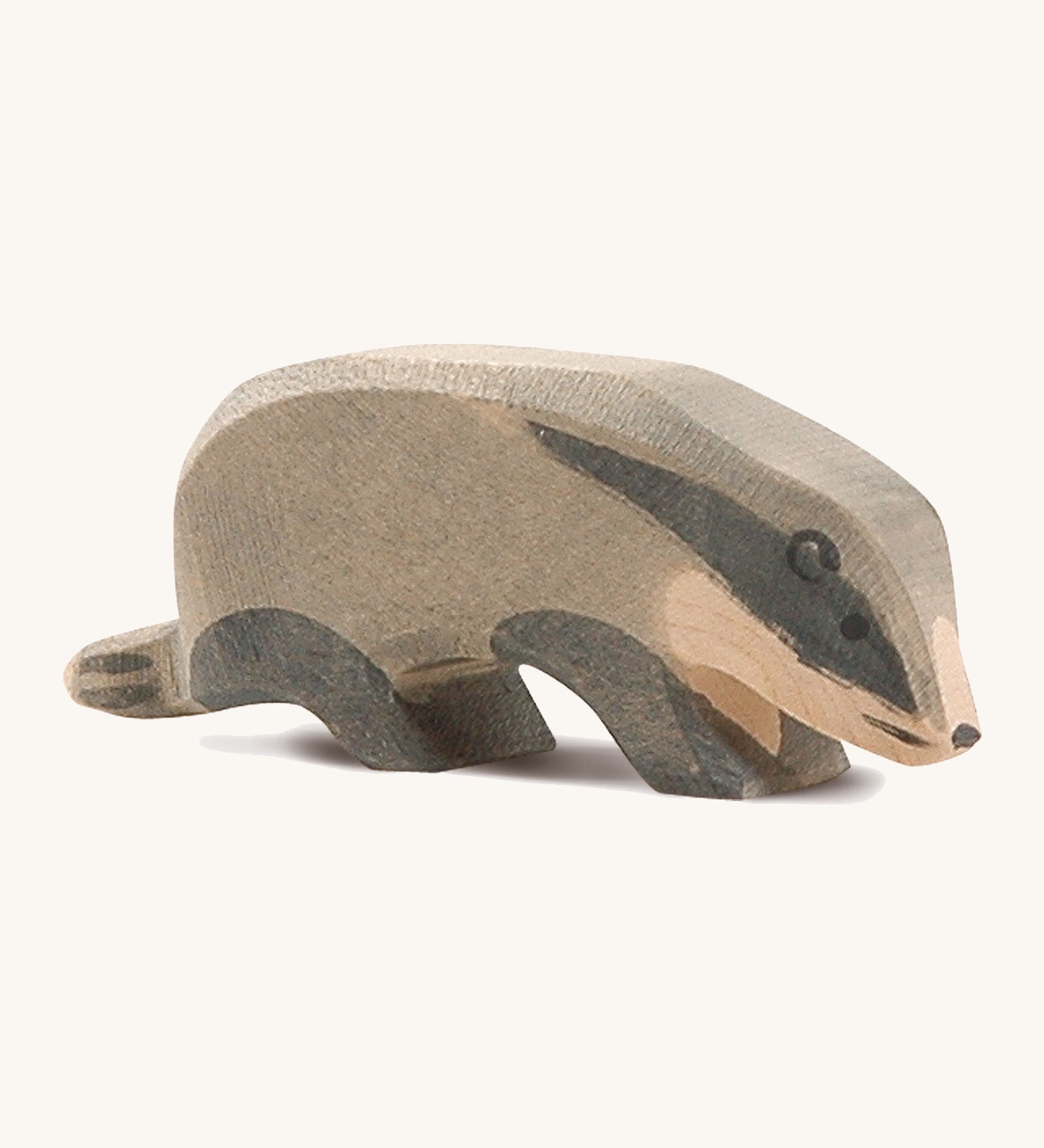 A wooden Ostheimer badger figure with its head low on a cream background.