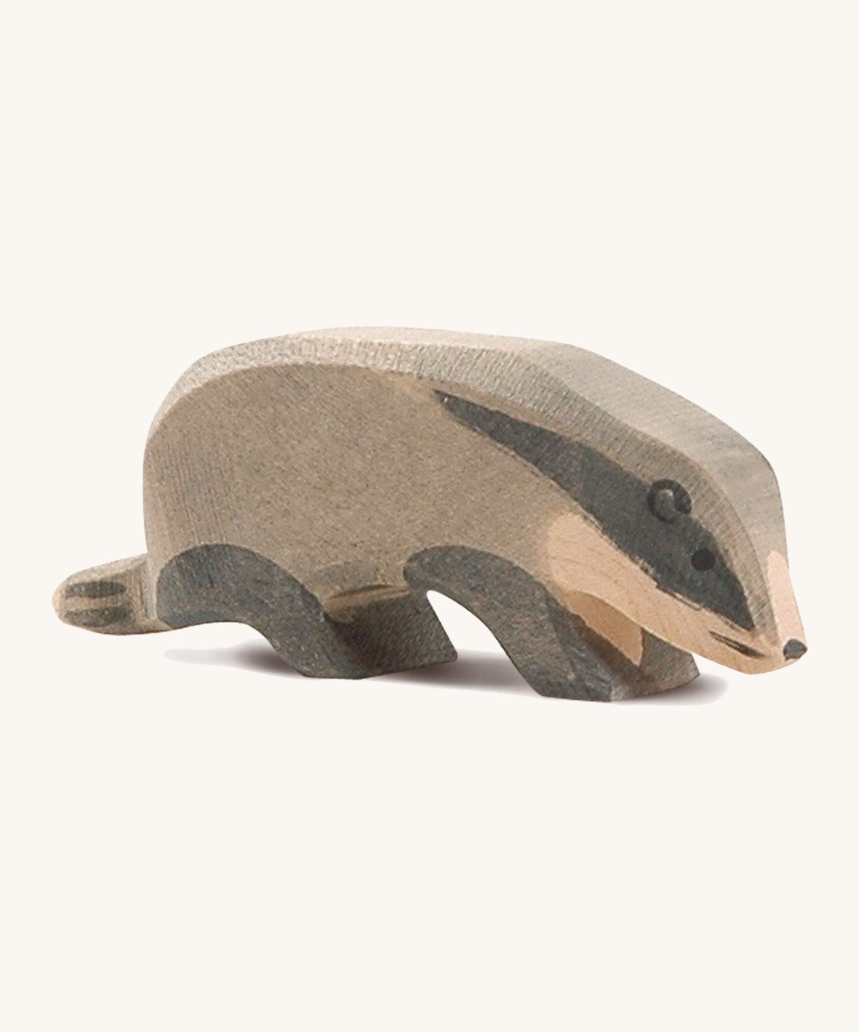 A wooden Ostheimer badger figure with its head low on a cream background.