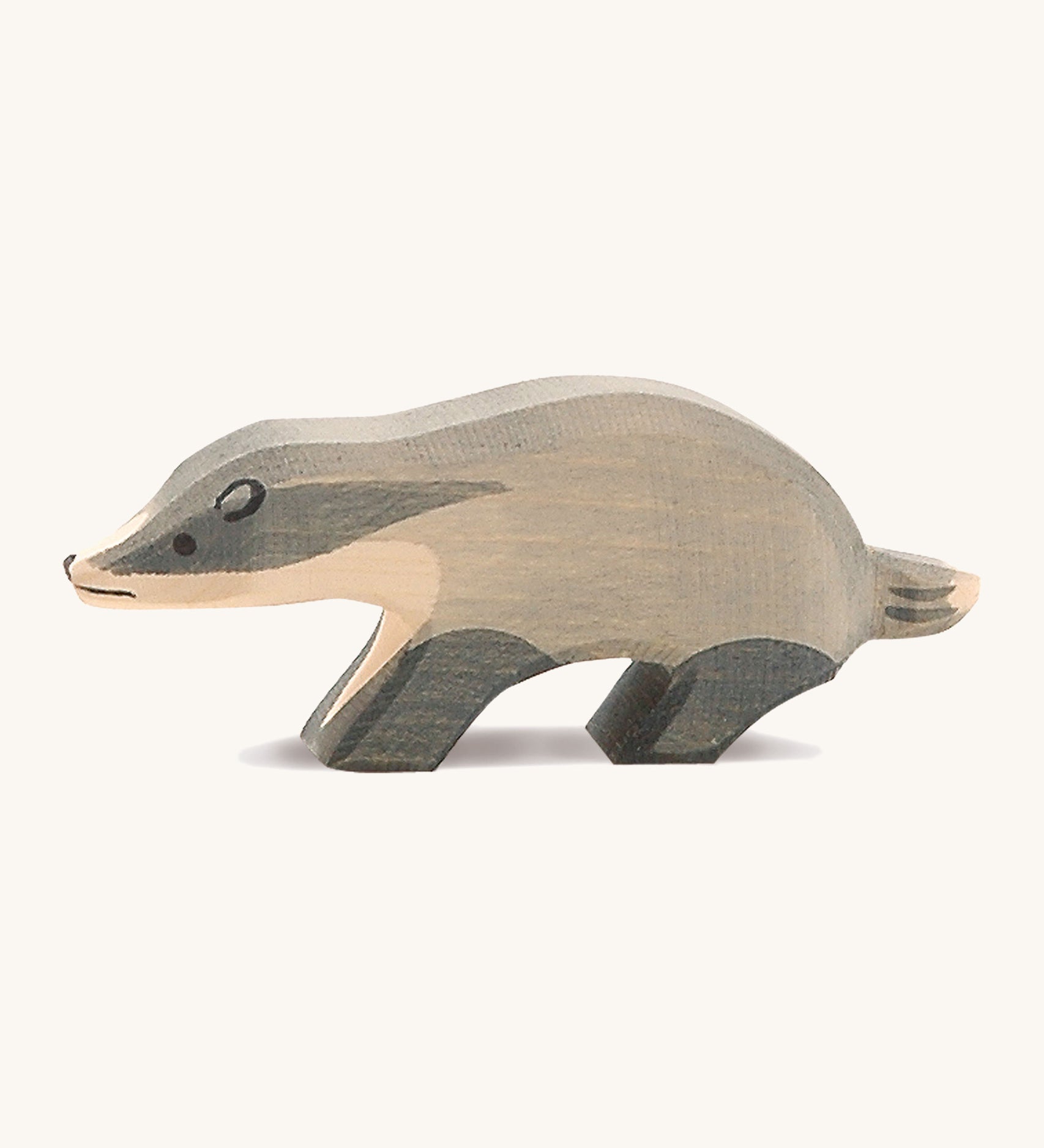 A wooden Ostheimer badger figure with its head straight on a cream background.