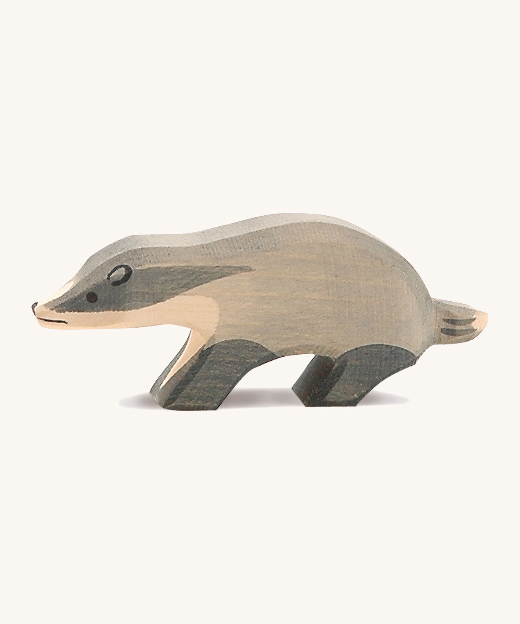 A wooden Ostheimer badger figure with its head straight on a cream background.