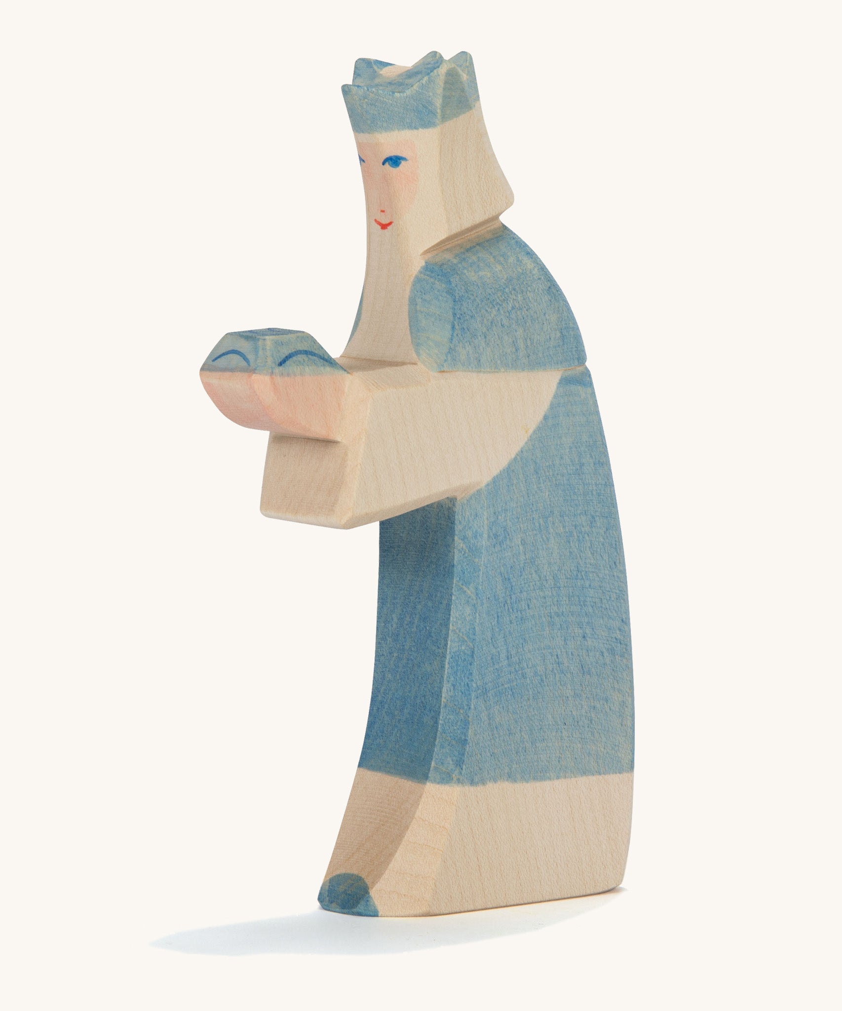 A Ostheimer wooden king figure wearing a blue gown and a blue crown on his head on a cream background.