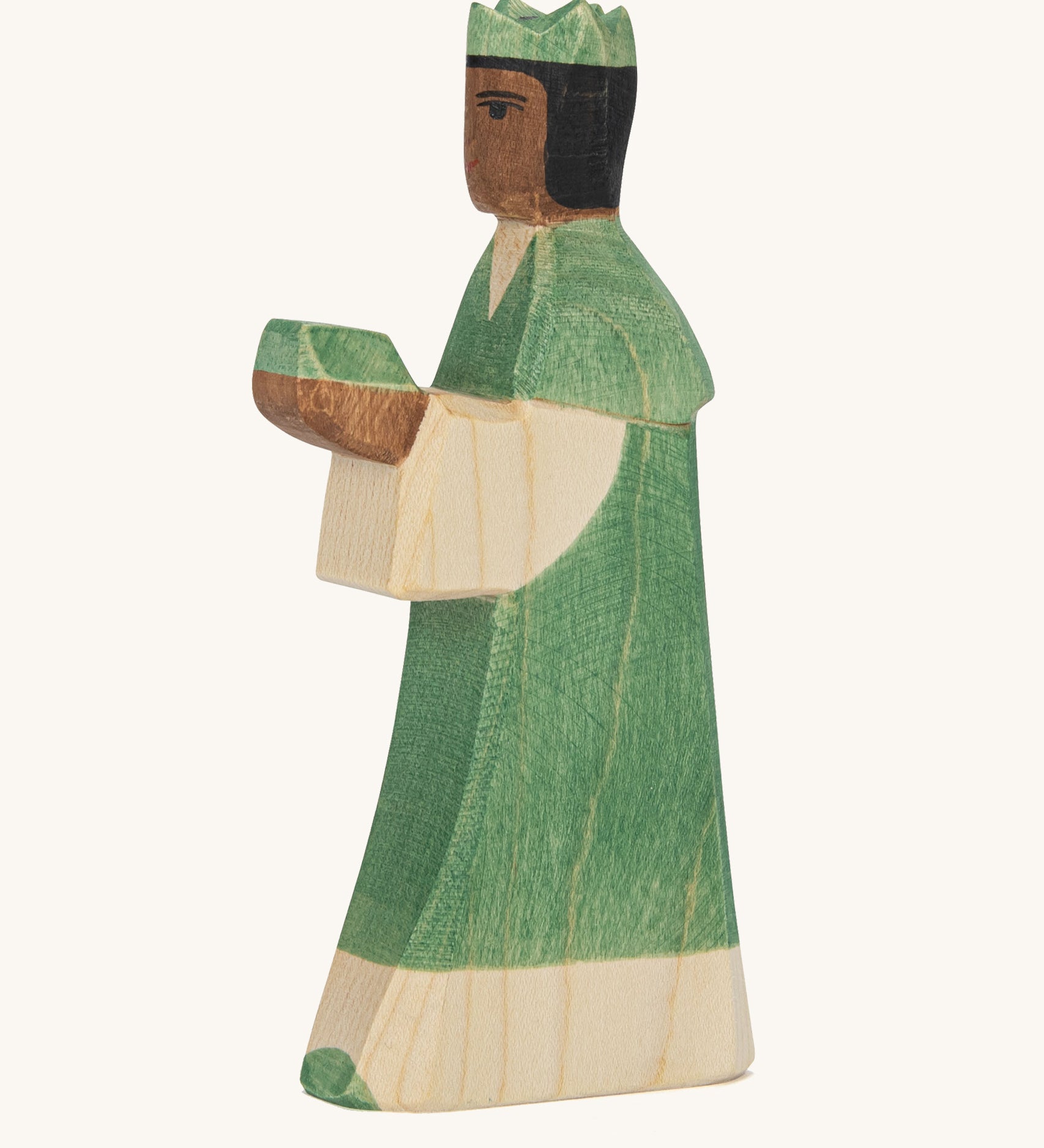 A Ostheimer wooden king figure wearing a green gown and a green crown on his head on a cream background.