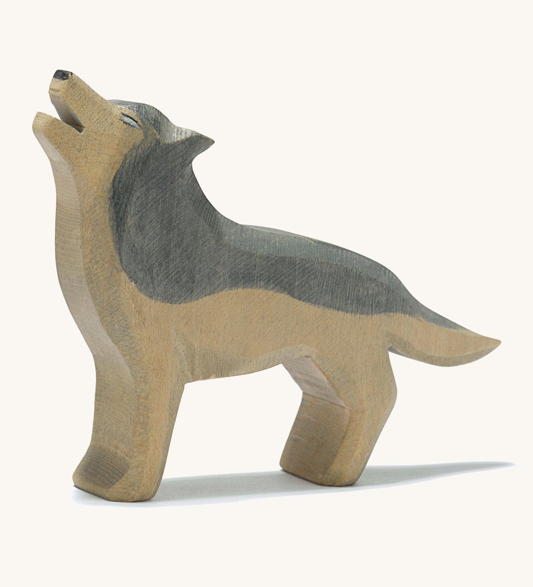 A wooden Ostheimer howling grey wolf figure on a cream background